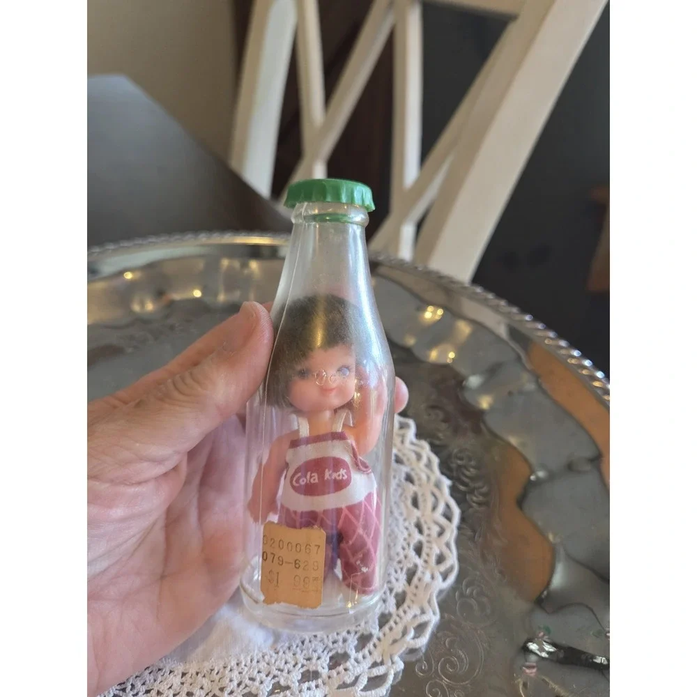vintage 1960s Cola Kids doll is encased in a clear plastic bottle